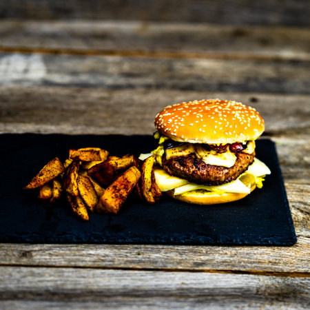 Tasty home made cheeseburger. Cheese burger with pickles, tomatoes, onion, melting cheeseの写真素材