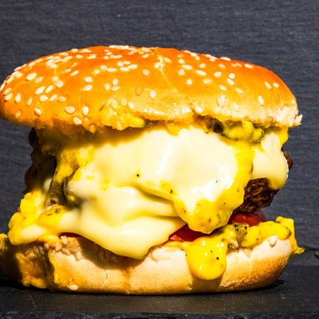 Tasty home made cheeseburger. Cheese burger with pickles, tomatoes, onion, melting cheeseの写真素材
