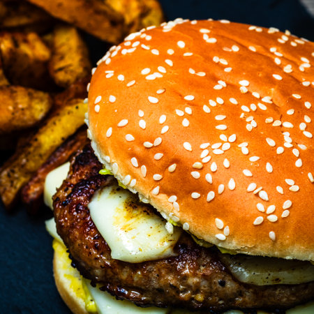 Tasty home made cheeseburger. Cheese burger with pickles, tomatoes, onion, melting cheeseの写真素材