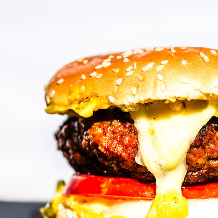 Tasty home made cheeseburger. Cheese burger with pickles, tomatoes, onion, melting cheeseの写真素材