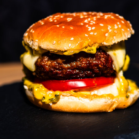 Tasty home made cheeseburger. Cheese burger with pickles, tomatoes, onion, melting cheeseの写真素材