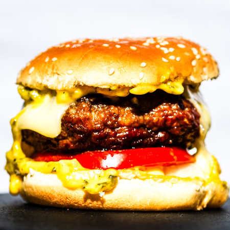 Tasty home made cheeseburger. Cheese burger with pickles, tomatoes, onion, melting cheeseの写真素材