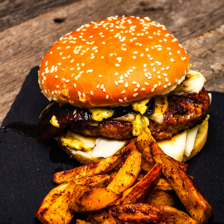 Tasty home made cheeseburger. Cheese burger with pickles, tomatoes, onion, melting cheeseの写真素材