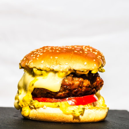 Tasty home made cheeseburger. Cheese burger with pickles, tomatoes, onion, melting cheeseの写真素材