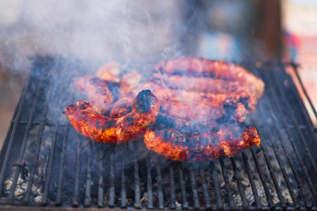 Grilling sausages on barbecue grill. Delicious sausages on charcoal grillの写真素材
