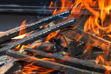 Barbecue grill pit with glowing and flaming hot open fire with red flame, hot charcoal briquettes and embersの写真素材