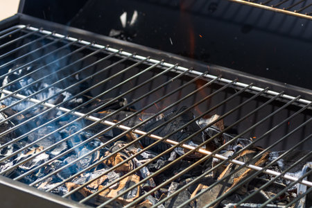 Barbecue grill pit with glowing and flaming hot open fire with red flame, hot charcoal briquettes and embersの写真素材