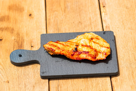 Close up of grilled steak on small black chopping board isolated. Barbecue, grill and food concept.の写真素材