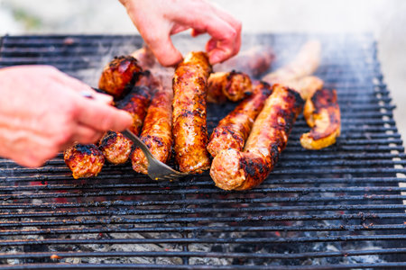 Grilling sausages on barbecue grill. Delicious sausages on charcoal grillの写真素材