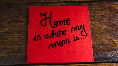 Writing Home is where my mom is on memo post reminder. Text on sticky paper. Mother`s day concept.