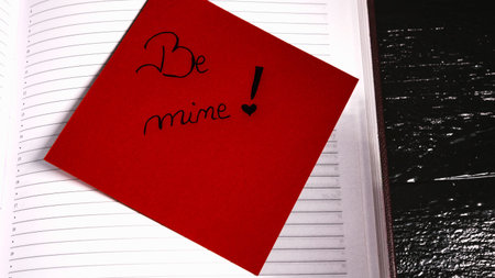 Writing be mine on memo post reminder. Text on sticky paper.