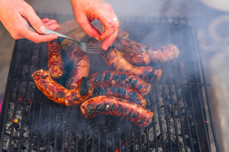 Grilling sausages on barbecue grill. Delicious sausages on charcoal grillの写真素材