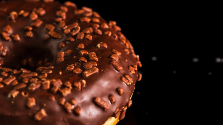 Chocolate glazed donut with chocolate chips isolated. Close up of delicious donut.の写真素材