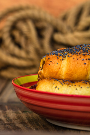 Sausages baked in dough sprinkled with salt and poppy seeds in a rustic composition. Sausages rolls, delicious homemade pastries.の写真素材
