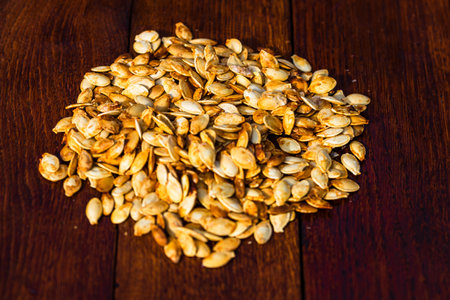 Roasted salty pumpkin seeds on wooden tableの写真素材