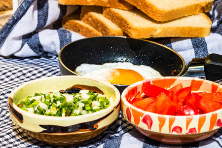 Close up of fried egg in a small frying pan  and different bowls with copped vegetables in a rustic compositionの写真素材
