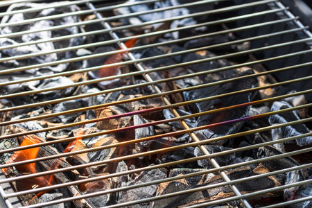 Barbecue grill pit with glowing and flaming hot open fire with red flame, hot charcoal briquettes and embersの写真素材