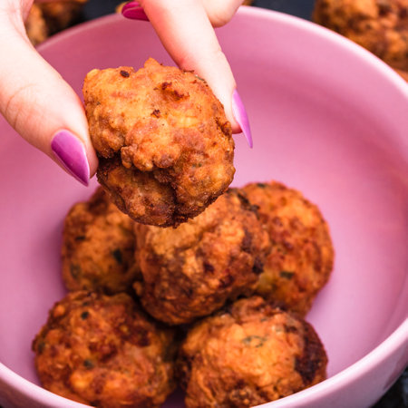 Pink bowl with fried meatballs with spices. Homemade food. Hand holding a fried meatball.の写真素材