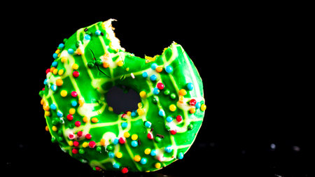 Green glazed donut with sprinkles isolated. Close up of colorful bitten donut.の写真素材
