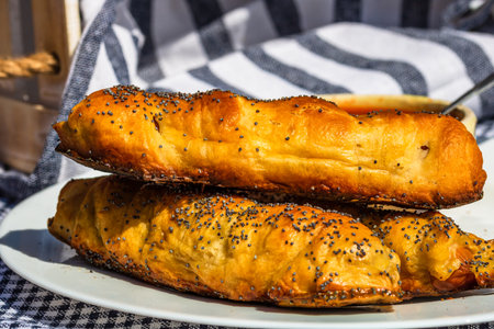 Sausages baked in dough sprinkled with salt and poppy seeds in a rustic composition. Sausages rolls, delicious homemade pastries.の写真素材