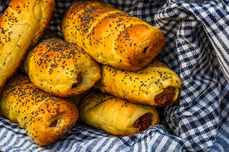 Sausages baked in dough sprinkled with salt and poppy seeds in a rustic basket. Sausages rolls, delicious homemade pastries in a rustic composition.の写真素材