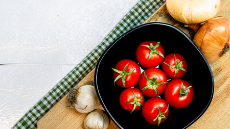 Top view of onions, garlic and fresh ripe cherry tomatoes on a rustic white wooden table. Ingredients and food conceptの写真素材