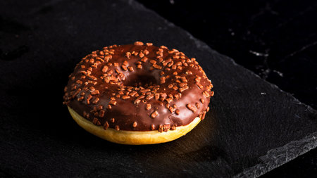 Chocolate glazed donut with chocolate chips isolated. Close up of delicious donut.の写真素材