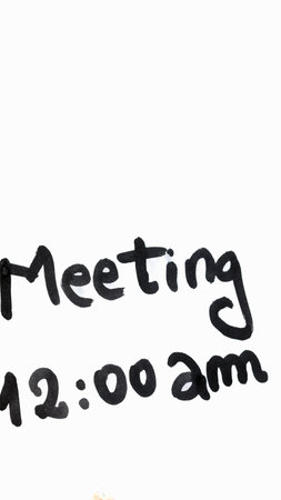 Meeting handwriting text close up isolated on white paper with copy space. Writing text on memo post reminderの写真素材