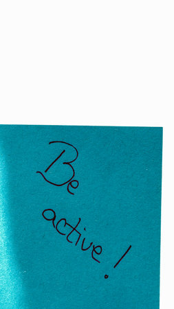 Be active handwriting text close up isolated on blue paper with copy space. Writing text on memo post reminderの写真素材