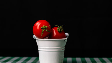 Selective focus on composition with mini decorative bucket and tomatoes. Small metal bucket with cherry tomatoesの写真素材