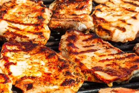 Grilling pork steaks. Delicious meat steaks close up cooking on the barbecue grillの写真素材