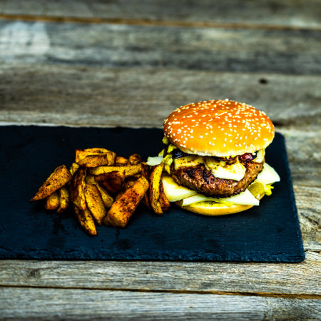 Tasty home made cheeseburger. Cheese burger with pickles, tomatoes, onion, melting cheeseの写真素材