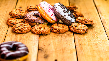 Colorful donuts on wooden table. Sweet icing sugar food with glazed sprinkles, doughnut with chocolate frosting. Top view with copy spaceの写真素材
