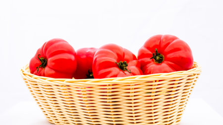 Fresh and tasty red tomatoes in wicker basket isolatedの写真素材