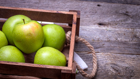 Wooden crate with ripe green apples on wooden table.の写真素材