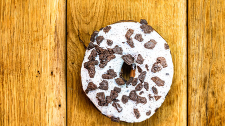 Colorful donuts on wooden table. Sweet icing sugar food with glazed sprinkles, doughnut with chocolate frosting. Top view with copy spaceの写真素材