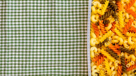 Tricolore fusilli, raw Italian pasta in plastic container, close up isolated in rustic compositionの写真素材