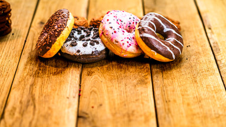 Colorful donuts on wooden table. Sweet icing sugar food with glazed sprinkles, doughnut with chocolate frosting. Top view with copy spaceの写真素材