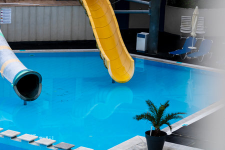 Clean swimming pool with clear blue water, bordered by white tiles and a striped deck, capturing the essence of a refreshing day at the poolの写真素材