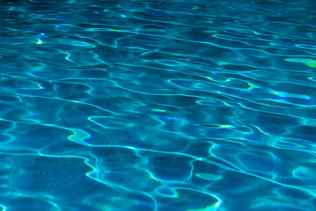 Blue swimming pool water surface and ripple wave background. Summer abstract reflection caustics in...