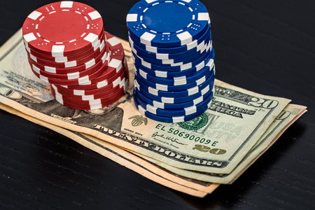 Stacks of poker chips with money on black background, US Dollar currencyの写真素材