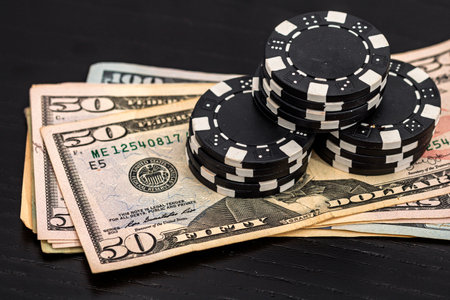 Stacks of poker chips with money on black background, US Dollar currencyの写真素材