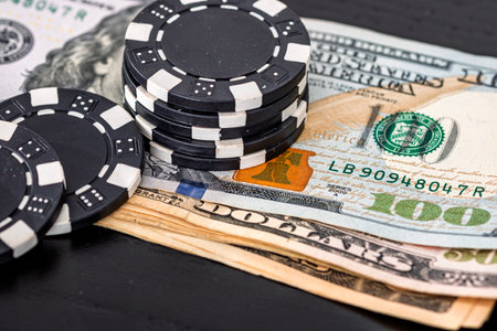 Stacks of poker chips with money on black background, US Dollar currencyの写真素材