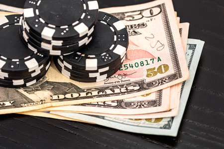 Stacks of poker chips with money on black background, US Dollar currencyの写真素材