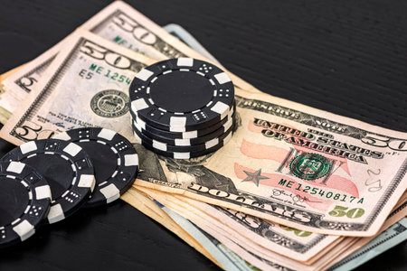 Stacks of poker chips with money on black background, US Dollar currencyの写真素材