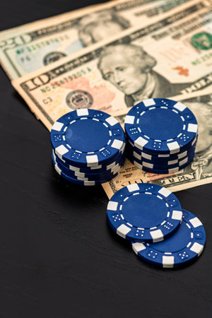 Stacks of poker chips with money on black background, US Dollar currencyの写真素材
