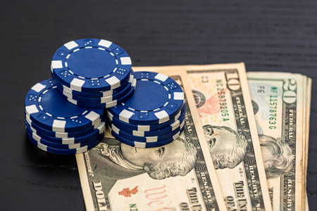 Stacks of poker chips with money on black background, US Dollar currencyの写真素材