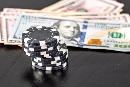 Stacks of poker chips with money on black background, US Dollar currencyの写真素材