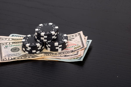 Stacks of poker chips with money on black background, US Dollar currencyの写真素材
