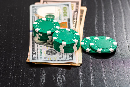 Stacks of poker chips with money on black background, US Dollar currencyの写真素材